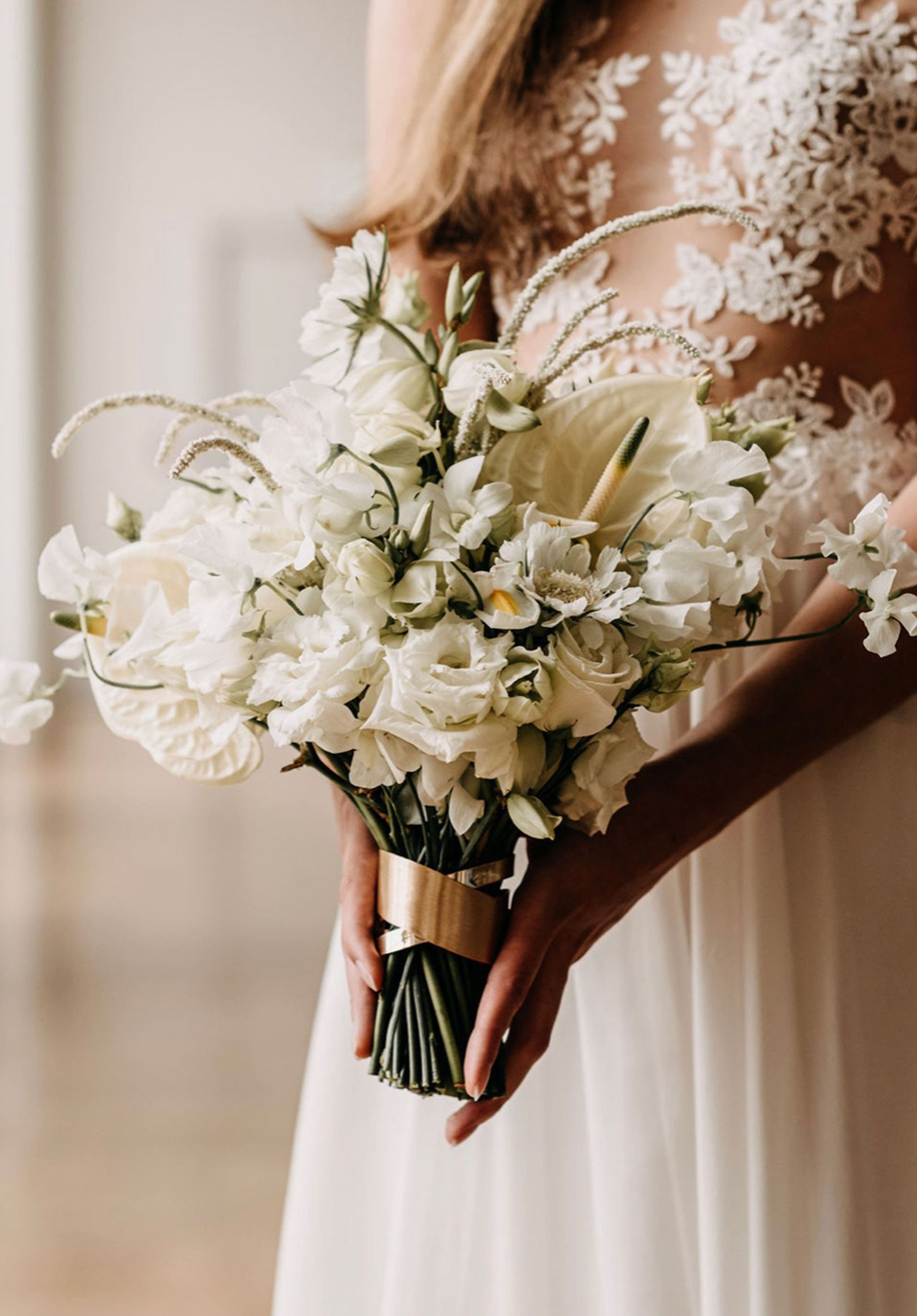 Brautstrauß aus Flamingoblumen und Rosen in Weiß, Braut im Hintergrund