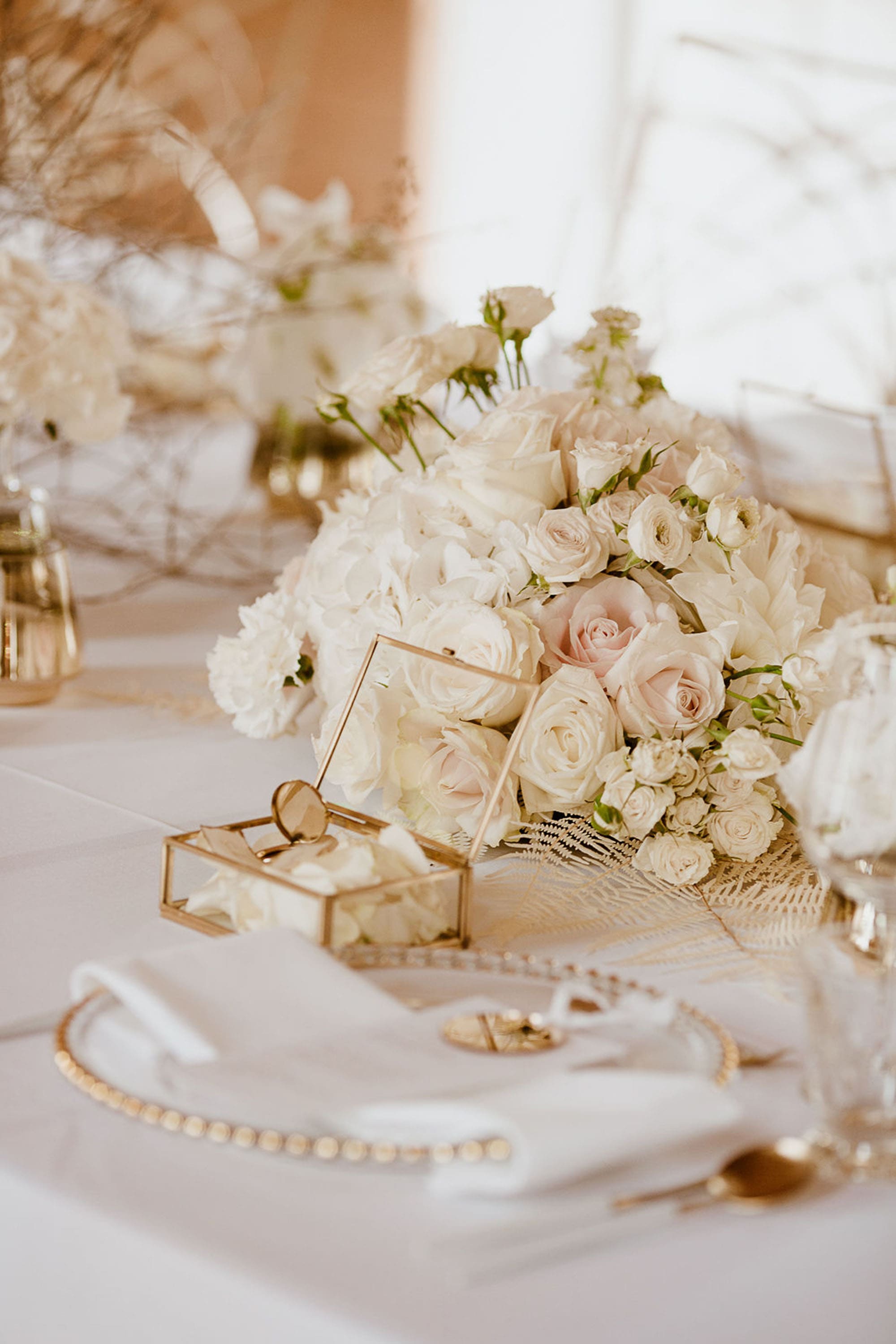 Tischgedeck mit weißen Rosen, Teller mit Goldrand und goldener Schatulle aus Glas